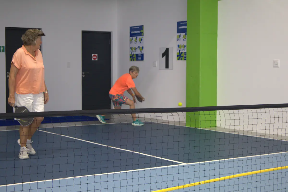 Two players in a rally on an indoor pickleball court