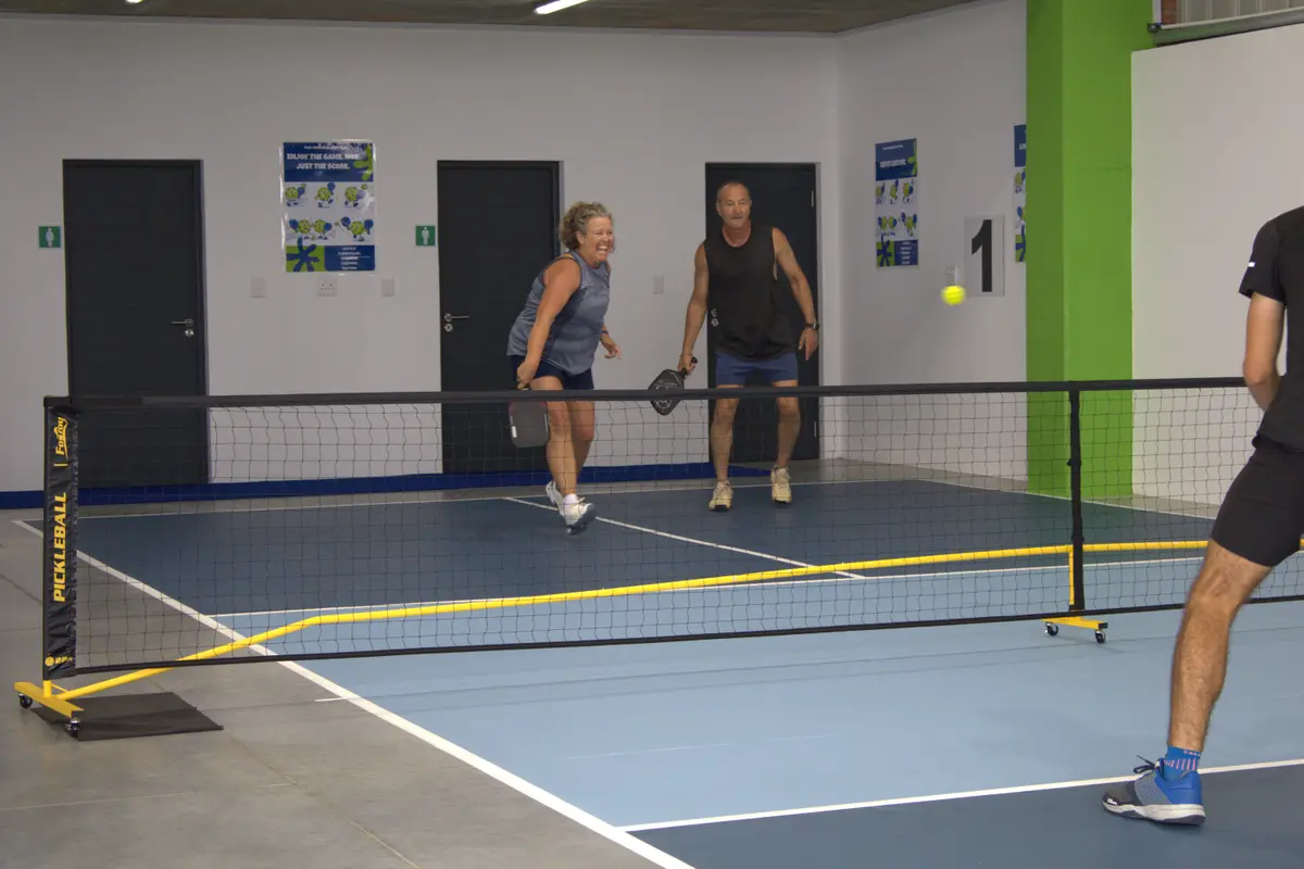 A doubles game of pickleball at an indoor venue
