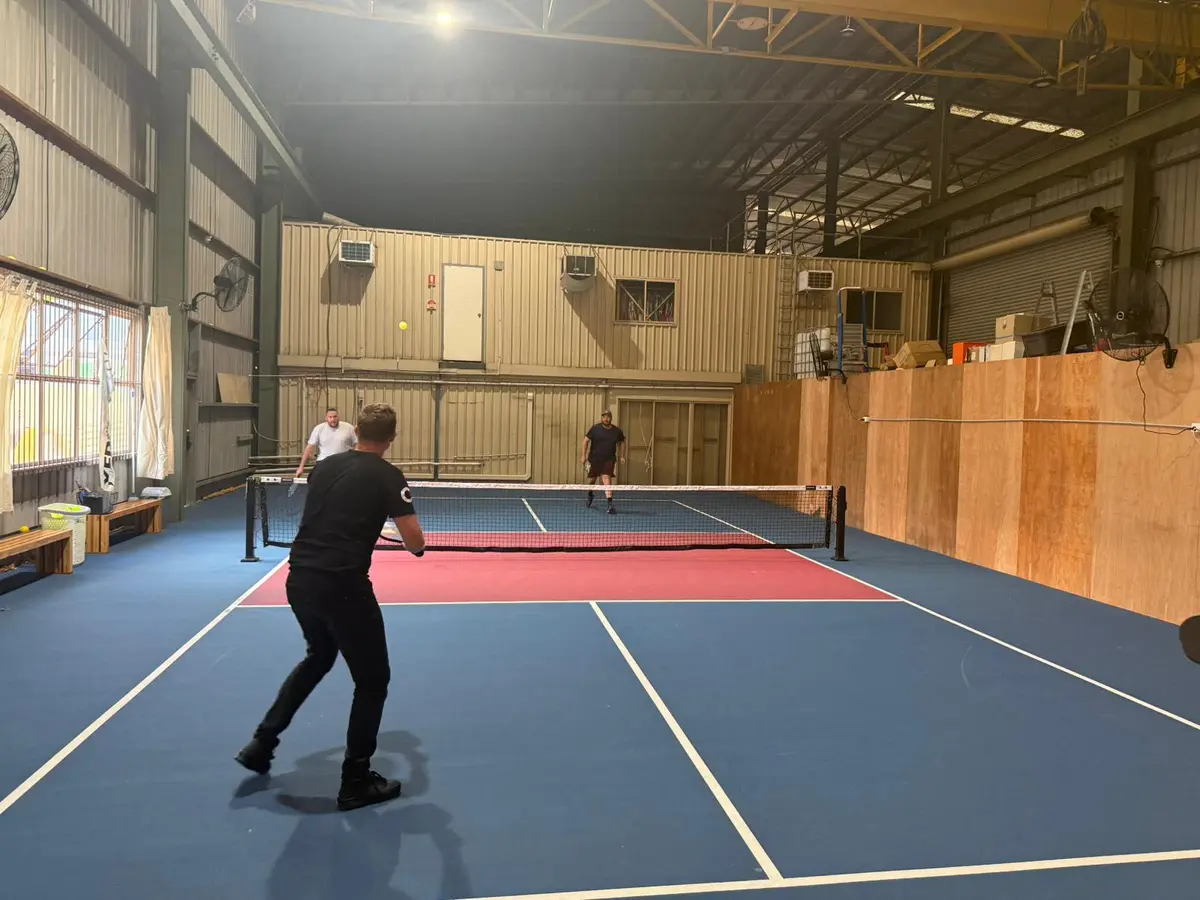 A player serving on an indoor pickleball court